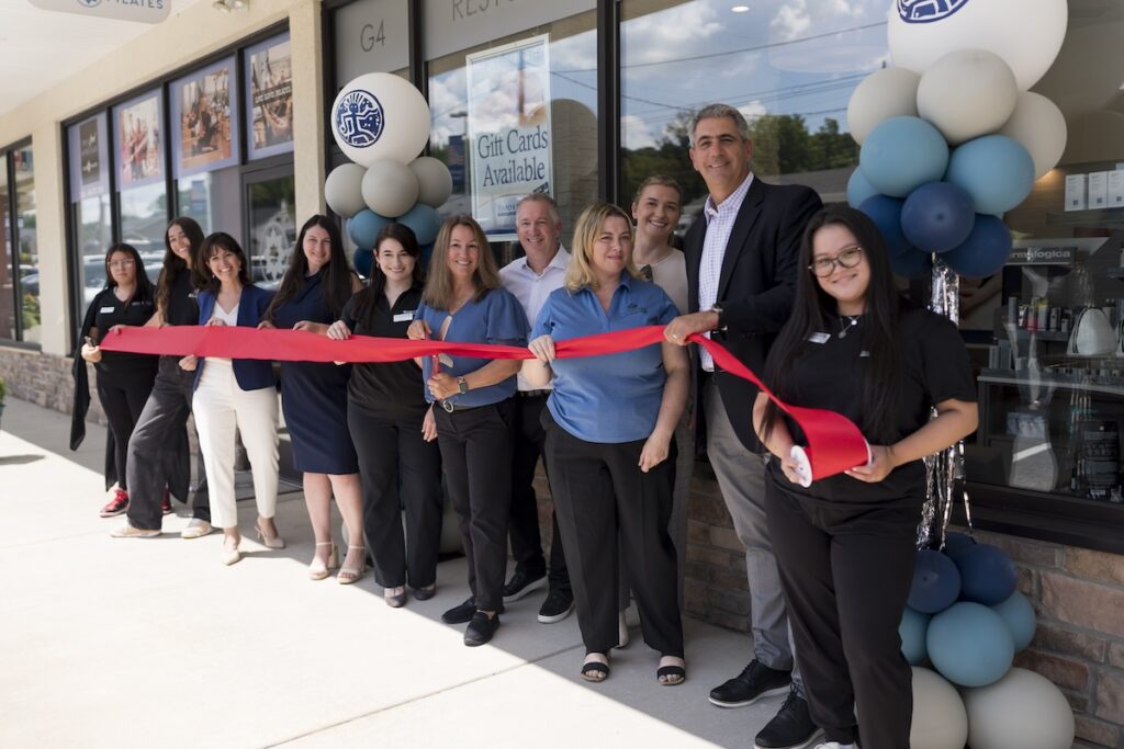 Franchise owners at red ribbon cutting ceremony with employees