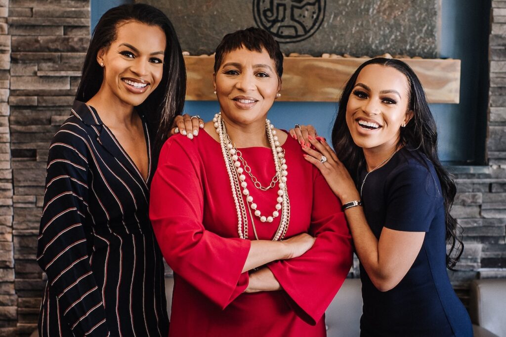 Three franchise owners smiling in front of storefront sign