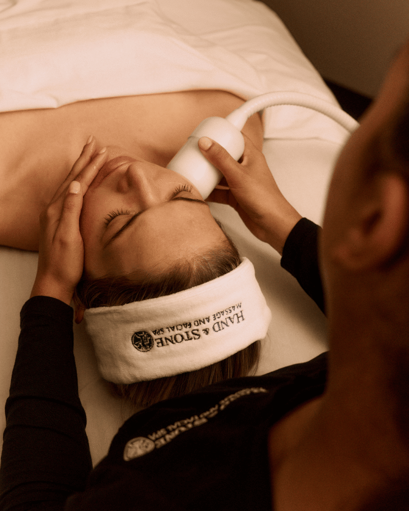 Woman getting a facial treatment done at Hand & Stone