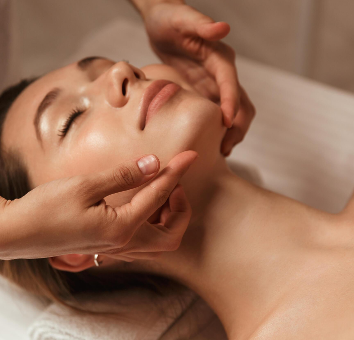 a technicians hands touching a woman's face during a facial.