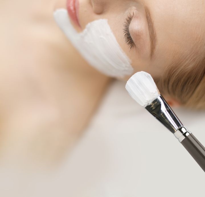 A white woman getting a skin treatment painted onto her face.